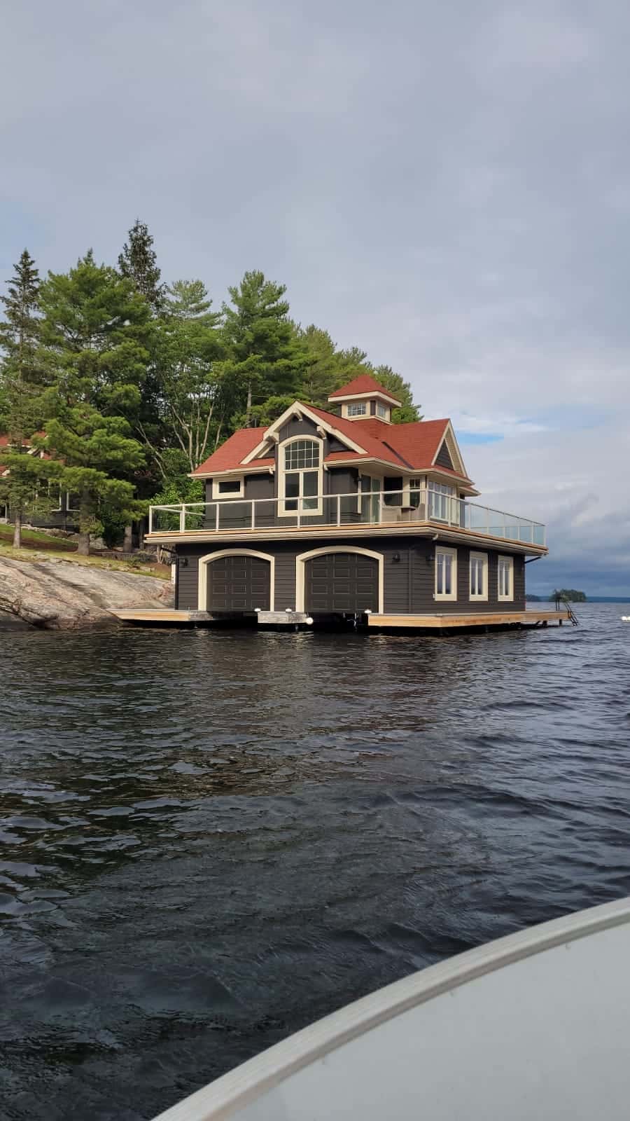 Red-roofed boathouse seen from the water showing two arched boat garage doors