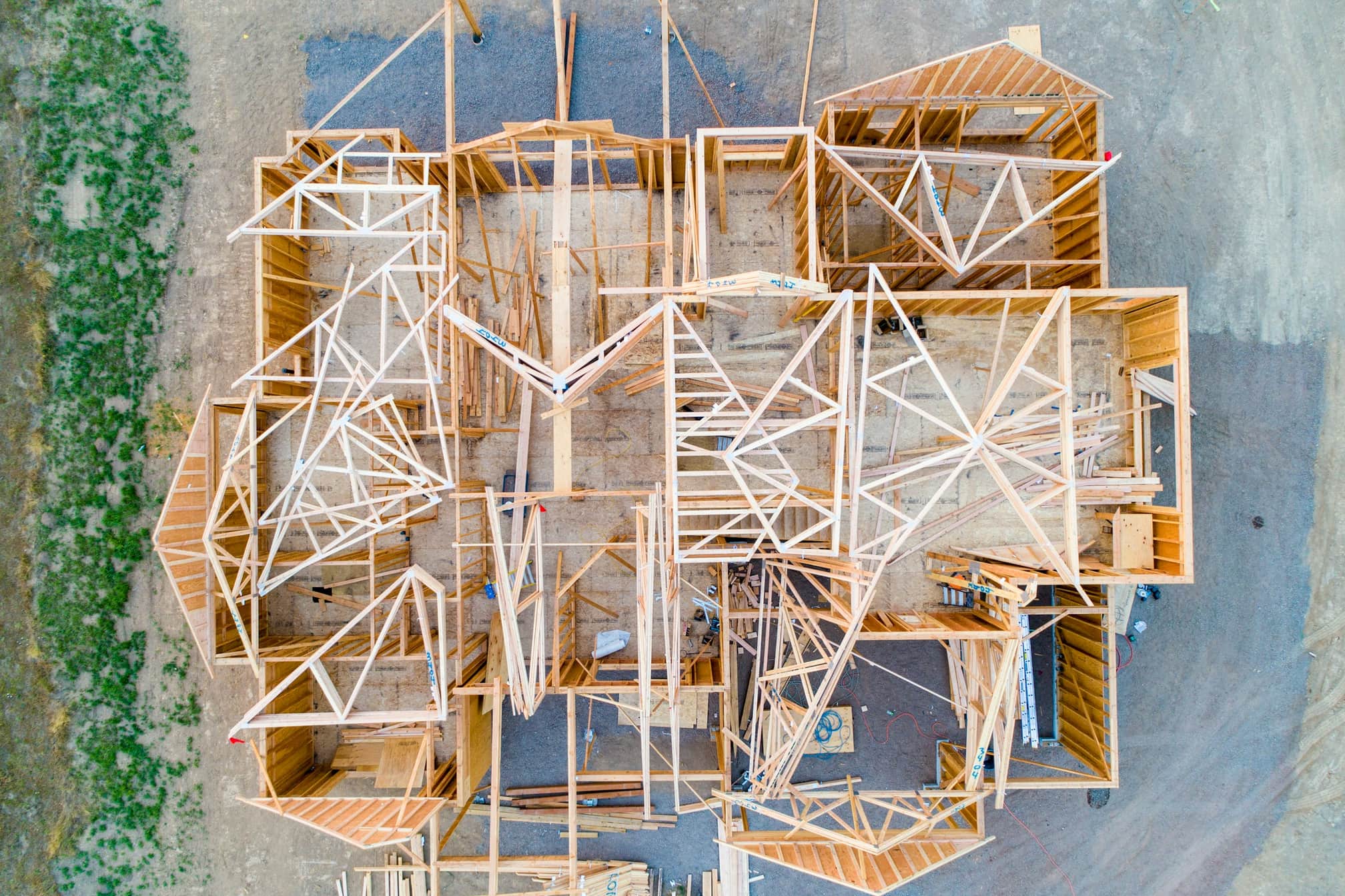 Aerial view of a house under construction, its floor plan drawn in fresh lumber framing