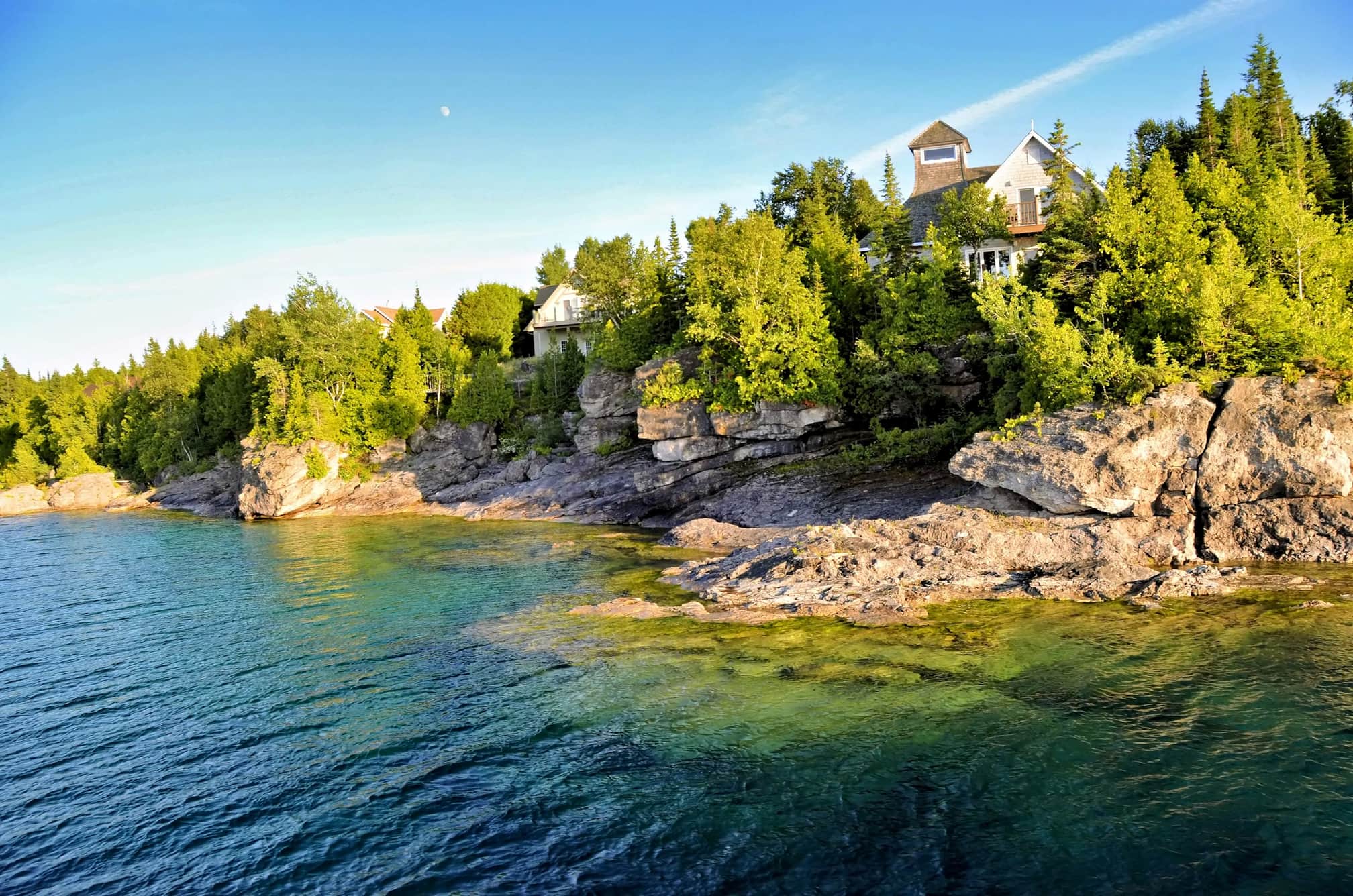Home with a lookout set in the trees above a rocky Canadian shoreline and clear water