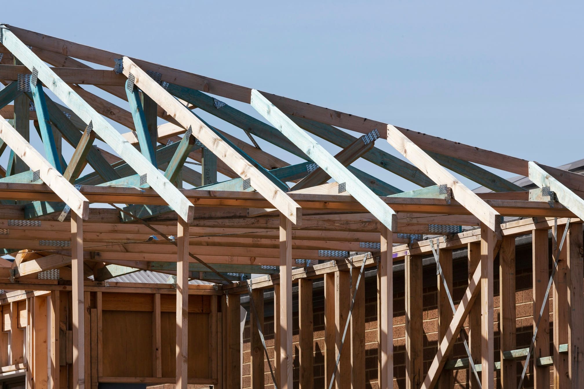 Roof framing in progress over a stud-framed house with bracing still on